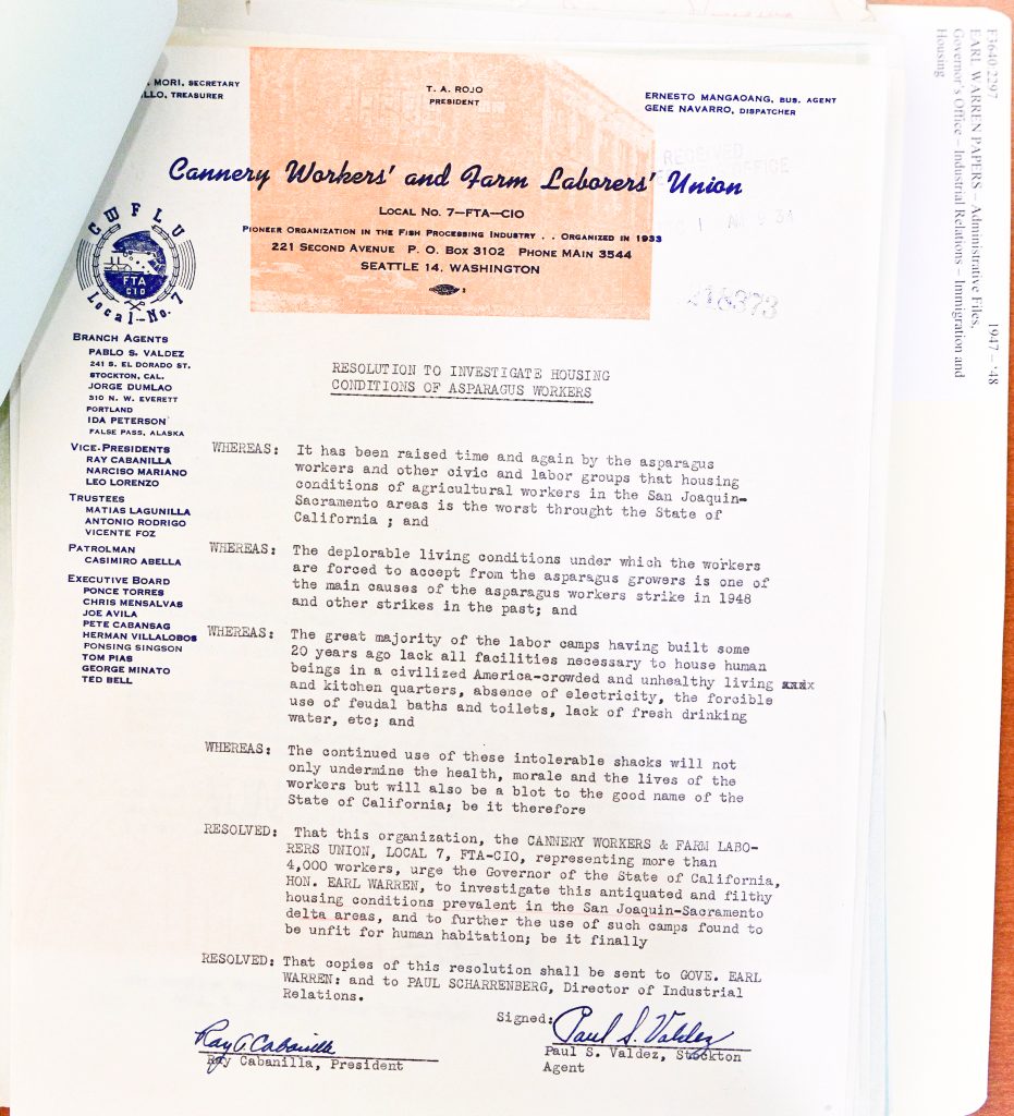 Cannery Workers’ and Farm Laborers’ Union Local No. 7 — FTA-CIO Pioneer Organization in the Fish Processing Industry — Organized in 1933 221 Second Avenue P. O. Box 3102 Phone Main 3544 Seattle 14, Washington RESOLUTION TO INVESTIGATE HOUSING CONDITIONS OF ASPARAGUS WORKERS WHEREAS: It has been raised time and again by the asparagus workers and other civic and labor groups that housing conditions of agricultural workers in the San Joaquin–Sacramento areas is the worst throughout the State of California; and WHEREAS: The deplorable living conditions under which the workers are forced to accept from the asparagus growers is one of the main causes of the asparagus workers strike in 1948 and other strikes in the past; and WHEREAS: The great majority of the labor camps having built some 20 years ago lack all facilities necessary to house human beings in a civilized manner, overcrowded and unhealthy living and kitchen quarters, absence of electricity, the forcible use of feudal baths and toilets, lack of fresh drinking water, etc.; and WHEREAS: The continued use of these intolerable shacks will not only undermine the health, morale and the lives of the workers but will also be a blot to the good name of the State of California; be it therefore RESOLVED: That this organization, the CANNERY WORKERS & FARM LABORERS UNION, LOCAL 7, FTA-CIO, representing more than 4,000 workers, urge the Governor of the State of California, HON. EARL WARREN, to investigate this antiquated and filthy housing conditions prevalent in the San Joaquin–Sacramento delta areas, and to further the use of such camps found to be unfit for human habitation; be it finally RESOLVED: That copies of this resolution shall be sent to GOVE. EARL WARREN and to PAUL SCHARRENBERG, Director of Industrial Relations. Signed: Ray Cabanilla, President Paul S. Valdez, Stockton Agent Detailed Description / Context: This labor union resolution reflects post–World War II agricultural labor struggles in California, particularly in the San Joaquin–Sacramento Delta, a major asparagus-producing region. The Cannery Workers’ and Farm Laborers’ Union, affiliated with the Congress of Industrial Organizations (CIO), was active in organizing agricultural and food-processing workers, many of whom were Filipino, Mexican, and other minority laborers. The document highlights severe deficiencies in labor camp housing, including overcrowding, lack of sanitation, and absence of basic utilities. These conditions were cited as a contributing factor to the 1948 asparagus workers’ strike, one of several labor actions aimed at improving wages, working conditions, and living standards. The resolution’s appeal to Governor Earl Warren and state officials underscores the role of government oversight in regulating labor and housing conditions. It also reflects broader efforts by labor unions to document and challenge systemic inequalities in California’s agricultural economy, particularly those affecting migrant and minority workers.